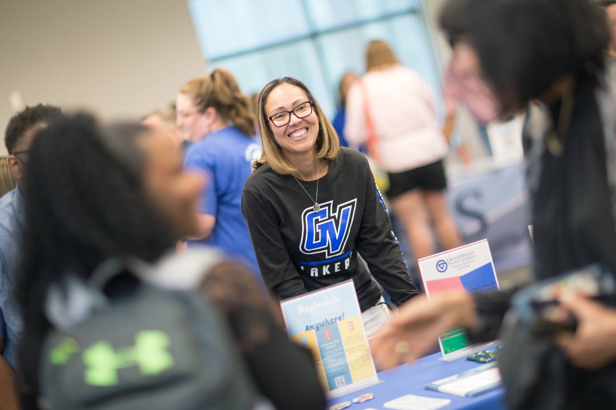 A woman behind a table and smiling while in conversation